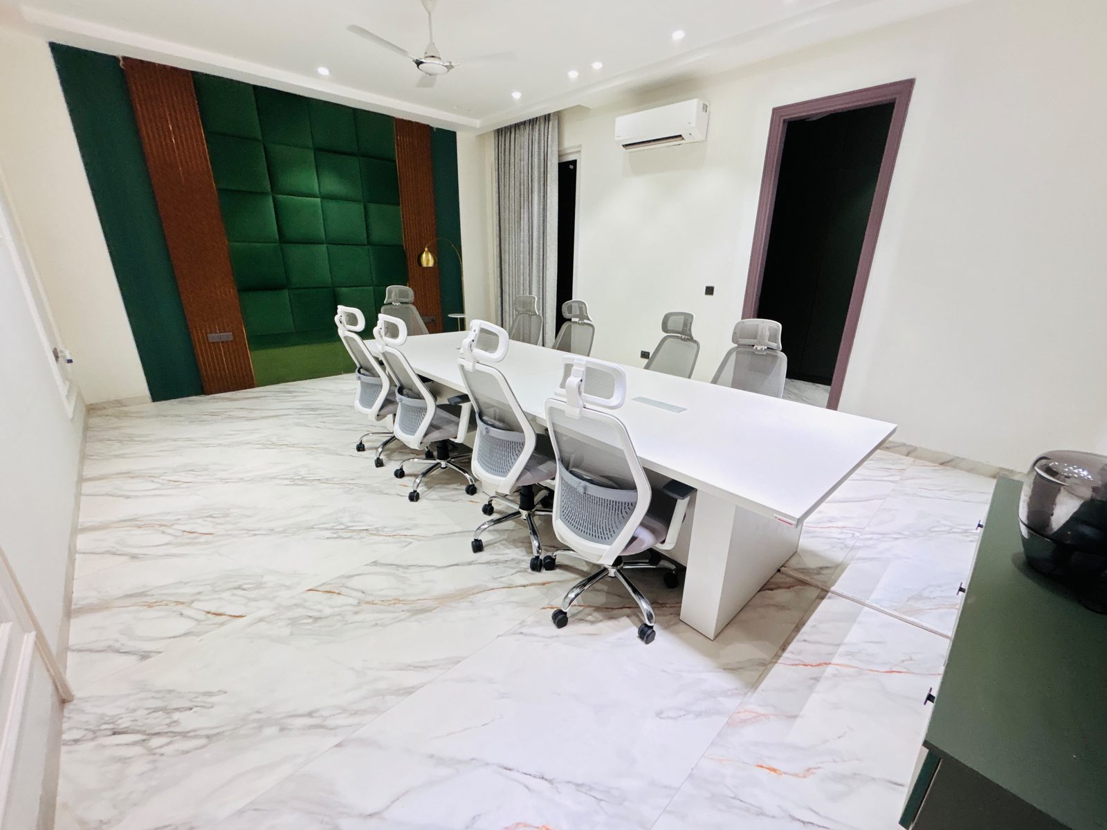 Villa boardroom with green padded wall and white conference table